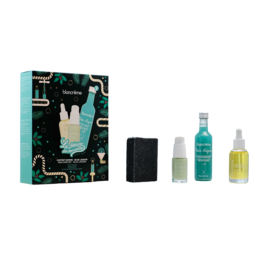 A gift set for men containing a blue lagoon-themed box, a black soap, a facial serum, and a facial oil. The set includes essential grooming products for a complete skincare routine.