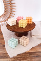  Colorful round pillar candles in various pastel shades including white, pink, yellow, orange, beige, mint, and light blue. The candles are arranged on a wooden display stand.