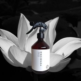 Cream-colored spray bottle with a white lotus flower in the background. The product is a 500ml room spray.