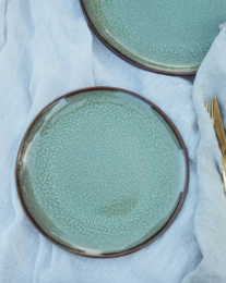 Round, green ceramic dinner plate with a textured glaze finish.