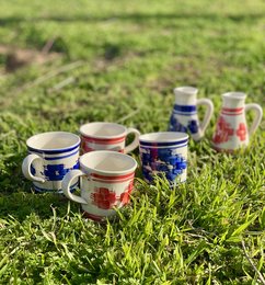 A set of handcrafted ceramic milk jars and cups in blue and red colors, featuring floral and geometric patterns, suitable for serving dairy products.