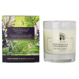 Scented candle with patchouli and cedarwood fragrance, presented in a glass container with a nature-inspired design.
