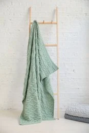 Soft, mint green merino wool throw with a cozy cable knit pattern, perfect for adding warmth and style to any room.