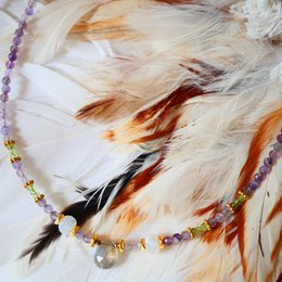 This necklace features a delicate chain with a mix of colorful gemstones including labradorite, amethyst, and peridot. The pendant is a natural stone with an organic shape, adding a unique and earthy touch to the design.