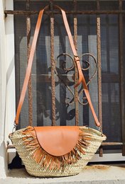  Tan leather handbag with woven straw fringe and braided leather straps.