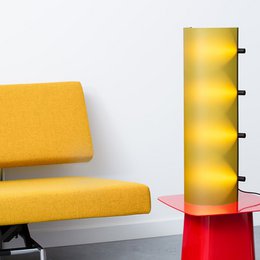  A tall, yellow lamp with a modern, minimalist design. The lamp features a sleek, rectangular shape and a warm, yellow glow that would complement a variety of interior styles.