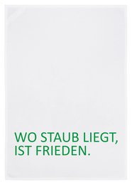 A white tea towel with the text "Wo staub liegt, ist frieden." (Where there is dust, there is peace) in green lettering.