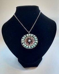 Mandala-inspired necklace with turquoise, silver, and brown beads in a circular design.