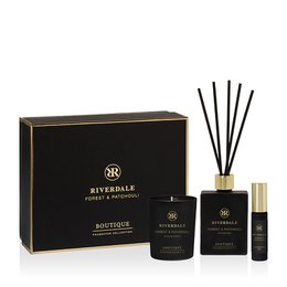  A gift box containing a forest and patchouli scented reed diffuser and candle set from the Riverdale brand. The set includes a black box, reed diffuser, and candle in a dark, earthy color palette.