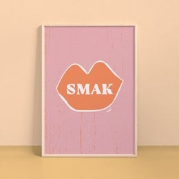 A vibrant pink poster featuring the word "SMAK" in an orange, stylized font. The poster has a minimalist, modern design that would complement a variety of home decor styles.