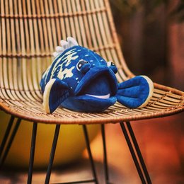 Plush blue fish-shaped toy with large eyes and fins, sitting on a woven chair.