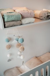 Soft, plush baby bedding display with pastel colors and textures. Includes shelving for storage and display.