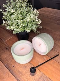 Concrete candles in a round, minimalist design with a floral arrangement. The candles are available in a light green color.
