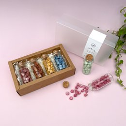 A set of mini bottles filled with colorful sealing wax beads for DIY crafting. The set includes a variety of colors such as red, yellow, blue, and more, packaged in a wooden box.
