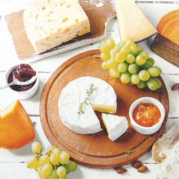  Assorted cheese, grapes, and other appetizers on a wooden board.