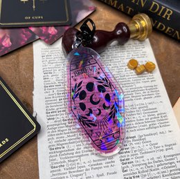 Colorful, iridescent keychain with a skull design and decorative charms. Made of glass or resin material, featuring a unique and eye-catching style.