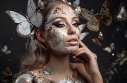 A surreal, artistic portrait of a woman with butterflies surrounding her face. The image has a dreamlike, ethereal quality, with the woman's expression and the butterflies creating a sense of wonder and mystery.