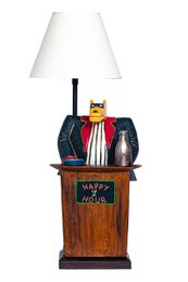  A wooden desk lamp with a black base and a white lamp shade. The lamp features a decorative figure of a wolf wearing a scarf and hat, sitting on a wooden podium.
