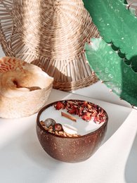 Coconut shell candle with a warm, tropical scent. Candle is round in shape and made from natural coconut shell material.