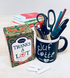A colorful, floral-patterned box labeled "Thanks a Lot" containing tea bags. The box features a red and green design with a flower motif.