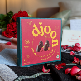 Organic date-based chocolates in a heart-shaped box, with a romantic design and rose petals surrounding the box.