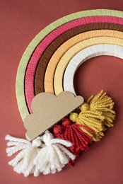 Colorful DIY rainbow/autumn craft kit with yarn tassels, pom-poms, and wooden shapes in a variety of vibrant hues.