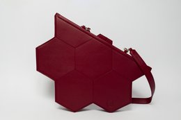 A burgundy red hexagonal handbag with a zipper closure and a strap for carrying.