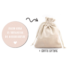 A small, decorative gift bag with a pink circular label that says "From the heart to the heart" in French. The bag is made of a light-colored fabric and has a drawstring closure.