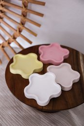  Decorative wooden candle plate with assorted pastel-colored flower-shaped candles in various shades of pink, yellow, and white.