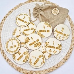 Milestone cards - floral, featuring a set of round wooden discs with floral designs and text indicating various milestones in a child's life.