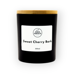 A tall, round black candle with a white label that says "Sweet Cherry Bark". The candle is made of premium materials and has a sweet cherry bark scent.