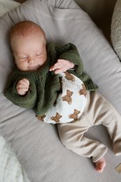 A semicircular natural hot water bottle filled with cherry pits, available in 4 colors - beige, brown, teddy, and teddy bears. This cozy and soothing pillow is perfect for babies and can provide warmth and comfort.