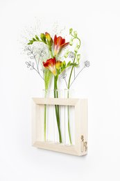 Vibrant red and yellow tulips in a wooden vase, with green foliage and white flowers. The tulips have a tall, slender shape and appear fresh and lively.