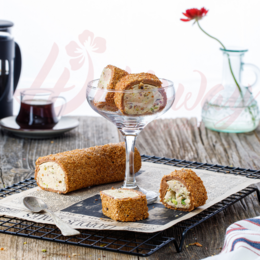 Sesame-coated gummy rolls with a creamy filling, served on a wooden plate.

The image shows a plate of sesame-coated gummy rolls or pastries. The rolls have a golden-brown exterior and appear to be filled with a creamy or soft filling. The plate is set on a wooden surface, and there is a cup of what looks like tea or coffee in the background.