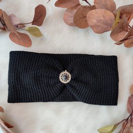 Black knitted headband with a decorative button in the center. The headband is designed for small to standard head sizes.
