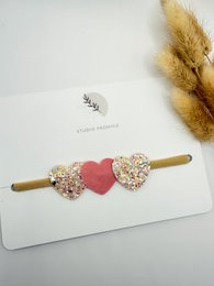  Hairband with two heart-shaped hair accessories in a neutral color palette, suitable for kids.