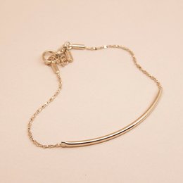 A delicate gold-toned tube bracelet with a minimalist design, featuring a variety of color variants including blanc, nude, mousse, noir, ambre, midnight blue, prusse, corail, aniline, brique, sable, and massaï.