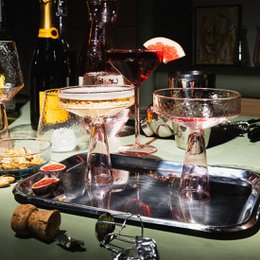 A set of two pink champagne glasses with a tall, coupe-style stem. The glasses have a delicate, elegant design and are suitable for serving champagne or other sparkling wines.