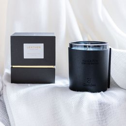 Premium leather scented candle with Nordic pine fragrance, presented in a sleek black container with gold accents.