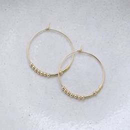 Gold-tone hoop earrings with beaded accents. Circular hoop shape with a delicate beaded detail along the outer edge. Suitable for casual or formal wear.