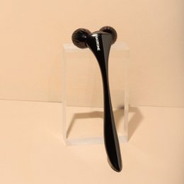  Black facial roller for skincare routine. Features a textured surface for massaging the skin.
