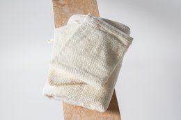 Soft, organic cotton washcloth in cream, gray, and beige colors with a textured, knitted pattern.
