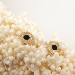 Hexagonal stud earrings in a variety of colors including Prusse, Ambre, Aniline, Corail, Blanc, Noir, Nude, Midnight Blue, Mousse, Brique, Sable, and Massaï. The earrings feature a simple, geometric design that complements a range of styles.