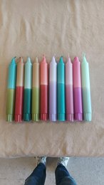 Colorful, cylindrical candles in various pastel shades including green, yellow, pink, and purple. The candles appear to be part of a "Neon '24 Collection" and are suitable for use as dinner candles.