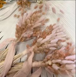 A bouquet of dried lagurus flowers in shades of pink and beige, tied with a ribbon.