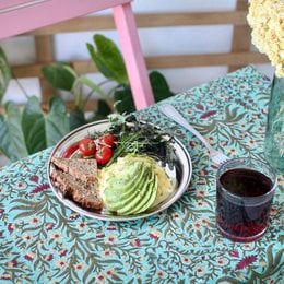 Round white ceramic plate with floral pattern, containing a meal with avocado and other ingredients.