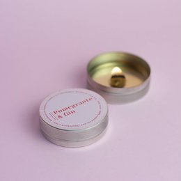 Mini scented soy candles in pomegranate and gin fragrance, round shape, gold-colored metal container.