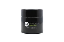 Organic matcha green tea powder in a black container with the brand name "Mindful Matcha" displayed.