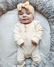 Cream ribbed romper for baby, available in sizes 0-3 months, 3-6 months, 6-9 months, 9-12 months, and 12-18 months. Made of soft, comfortable material with a ribbed texture. Features a snap closure for easy dressing.