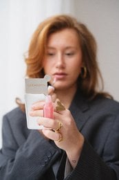 Oval-shaped makeup mirror with silver frame and pink accent. Compact and portable design for on-the-go use.